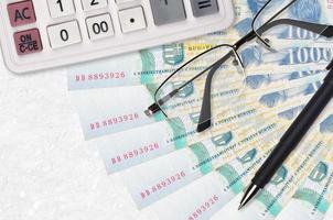 1000 Hungarian forint bills fan and calculator with glasses and pen. Business loan or tax payment season concept photo