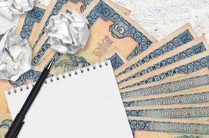 5 Ukrainian hryvnias bills and balls of crumpled paper with blank notepad. Bad ideas or less of inspiration concept. Searching ideas for investment photo