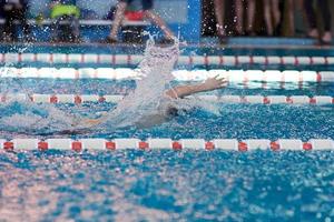 a beanie swimmer stretches out his arms during a breaststroke workout in the pool, blurred focus photo