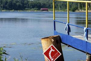 Wooden bridge on the lake shore, water intake sign for fire engines photo