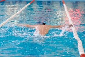 a swimmer waves his arms while performing a butterfly at a training session in the pool, blurred focus photo