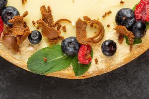 Homemade classic cheesecake on dark background. Decorating sweet cake with fresh berries photo