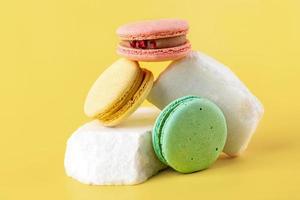 Macaroons laid out on stones on a yellow background. photo