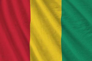 Guinea flag with big folds waving close up under the studio light indoors. The official symbols and colors in banner photo