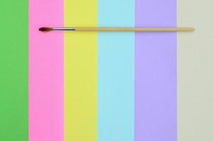 A new paint brush lie on texture background of fashion pastel pink, blue, green, yellow, violet and beige colors paper in minimal concept. Abstract trendy pattern photo