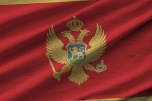 bandera de montenegro con grandes pliegues ondeando de cerca bajo la luz del estudio en el interior. los símbolos y colores oficiales en banner foto