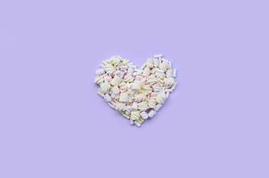 Colorful marshmallow laid out on violet and pink paper background. pastel creative textured heart. minimal photo