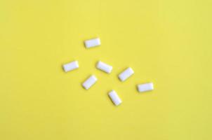 A few chewing gums lie on texture background of fashion pastel yellow color paper in minimal concept photo