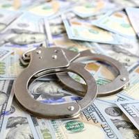 Silver police handcuffs lies on a many dollar bills photo