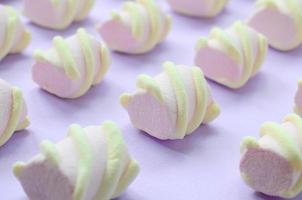 Colorful marshmallow laid out on violet paper background. pastel creative textured pattern. Perspective macro shot photo