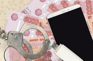 5000 russian rubles bills and smartphone with police handcuffs. Concept of hackers phishing attacks, illegal scam or malware soft distribution photo