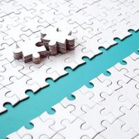 The blue path is laid on the platform of a white folded jigsaw puzzle. The missing elements of the puzzle are stacked nearby. Texture image with space for text photo