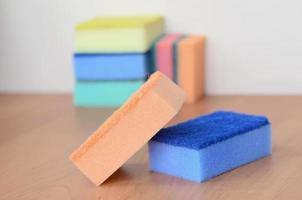 A few kitchen sponges lie on a wooden kitchen countertop. Colorful objects for washing dishes and cleaning in the house are ready for use photo