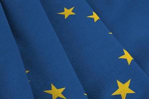 European union flag with big folds waving close up under the studio light indoors. The official symbols and colors in banner photo