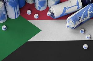 Sudan flag and few used aerosol spray cans for graffiti painting. Street art culture concept photo