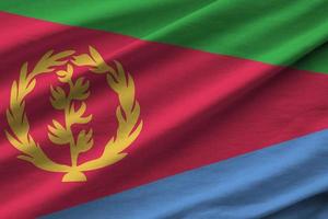 Eritrea flag with big folds waving close up under the studio light indoors. The official symbols and colors in banner photo