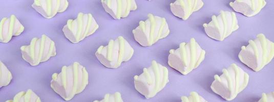 Colorful marshmallow laid out on violet paper background. pastel creative textured pattern. Perspective macro shot photo