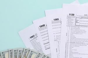 Tax forms lies near hundred dollar bills and blue pen on a light blue background. Income tax return photo