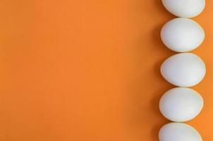 algunos huevos de pascua blancos sobre un fondo naranja brillante foto