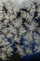 Snowflakes frost rime macro on window glass pane photo