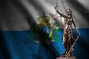 San Marino flag with statue of lady justice and judicial scales in dark room. Concept of judgement and punishment photo