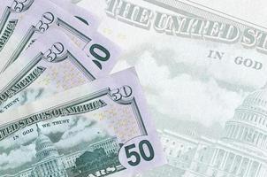 50 US dollars bills lies in stack on background of big semi-transparent banknote. Abstract business background photo