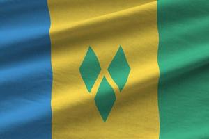 Saint Vincent and the Grenadines flag with big folds waving close up under the studio light indoors. The official symbols and colors in banner photo