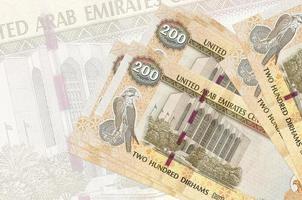 200 UAE dirhams bills lies in stack on background of big semi-transparent banknote. Abstract presentation of national currency photo