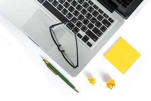 Isolated computer desktop with glasses pen and notepad on white background photo