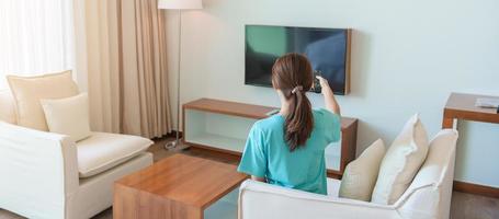 Woman relaxing on the couch, Girl using remote control and choosing TV show and movie series during rest on sofa in the morning. Apartment living concept photo