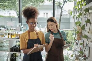 Two young female shopkeepers check stock of natural organic products in reusable containers shelves at refill store, zero waste, plastic-free grocery shop, and eco-friendly, sustainable lifestyles. photo