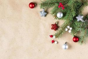 corner of fir tree branch with silver and red decoration on craft paper for christmas card with copy space for text. photo