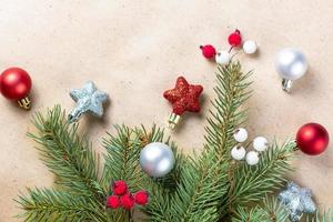 border of fir tree branch with silver and red decoration on craft paper for christmas card with copy space for text. photo