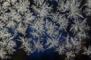 Snowflakes frost rime macro on window glass pane photo