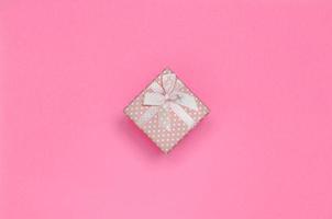 Small pink gift box lie on texture background of fashion pastel pink color paper in minimal concept photo