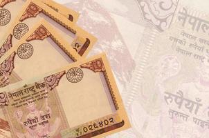 10 Nepalese rupees bills lies in stack on background of big semi-transparent banknote. Abstract business background photo