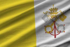 Vatican City State flag with big folds waving close up under the studio light indoors. The official symbols and colors in banner photo