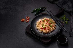 Delicious fresh noodles with sweet pepper, tomato, spices and herbs photo