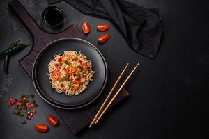 Delicious fresh noodles with sweet pepper, tomato, spices and herbs photo