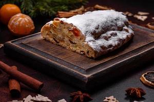 Christmas pie stollen with marzipan, berries and nuts on a dark concrete background photo