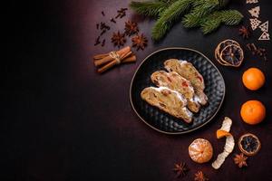 Christmas pie stollen with marzipan, berries and nuts on a dark concrete background photo