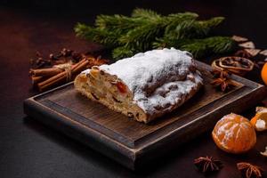 pastel de Navidad robado con mazapán, bayas y nueces sobre un fondo de hormigón oscuro foto