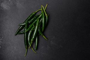 Hot pepper of green color on a dark concrete background photo
