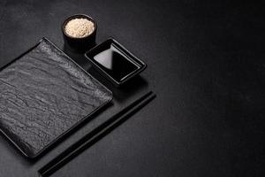 Empty plate with wooden sticks for Asian food on a dark concrete background photo