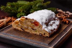 Christmas pie stollen with marzipan, berries and nuts on a dark concrete background photo