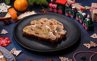 Delicious festive New Year's pie with candied fruits, marzipan and nuts on a dark concrete background photo