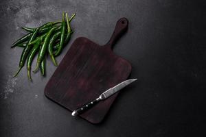 Hot pepper of green color on a dark concrete background photo