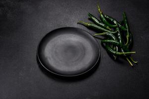 Hot pepper of green color on a dark concrete background photo