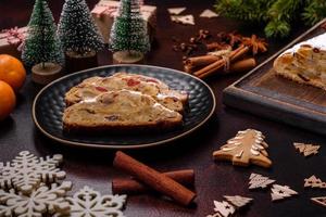 Christmas pie stollen with marzipan, berries and nuts on a dark concrete background photo