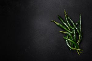Hot pepper of green color on a dark concrete background photo